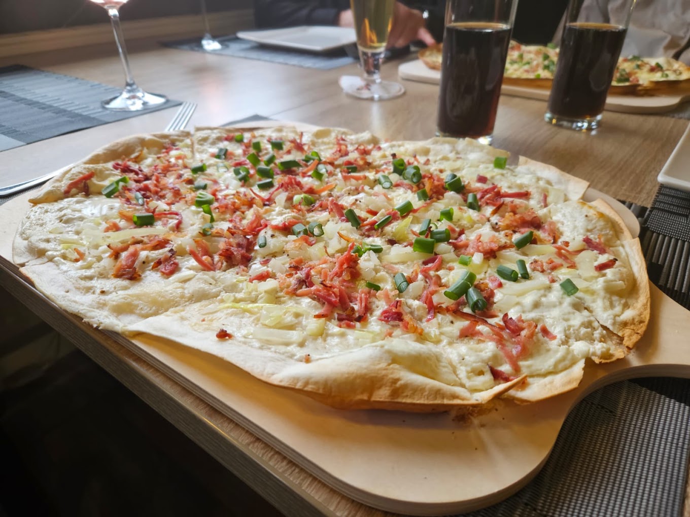 Großer Flammkuchen auf einem Holzbrett